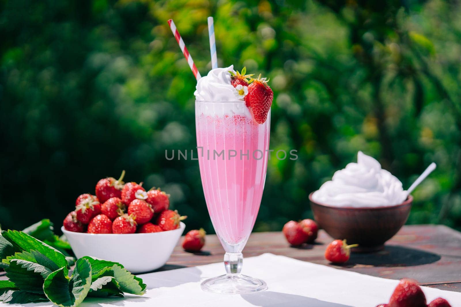 Still life - amazing strawberry milkshake cocktail with straw on nature backdrop by kristina_kokhanova