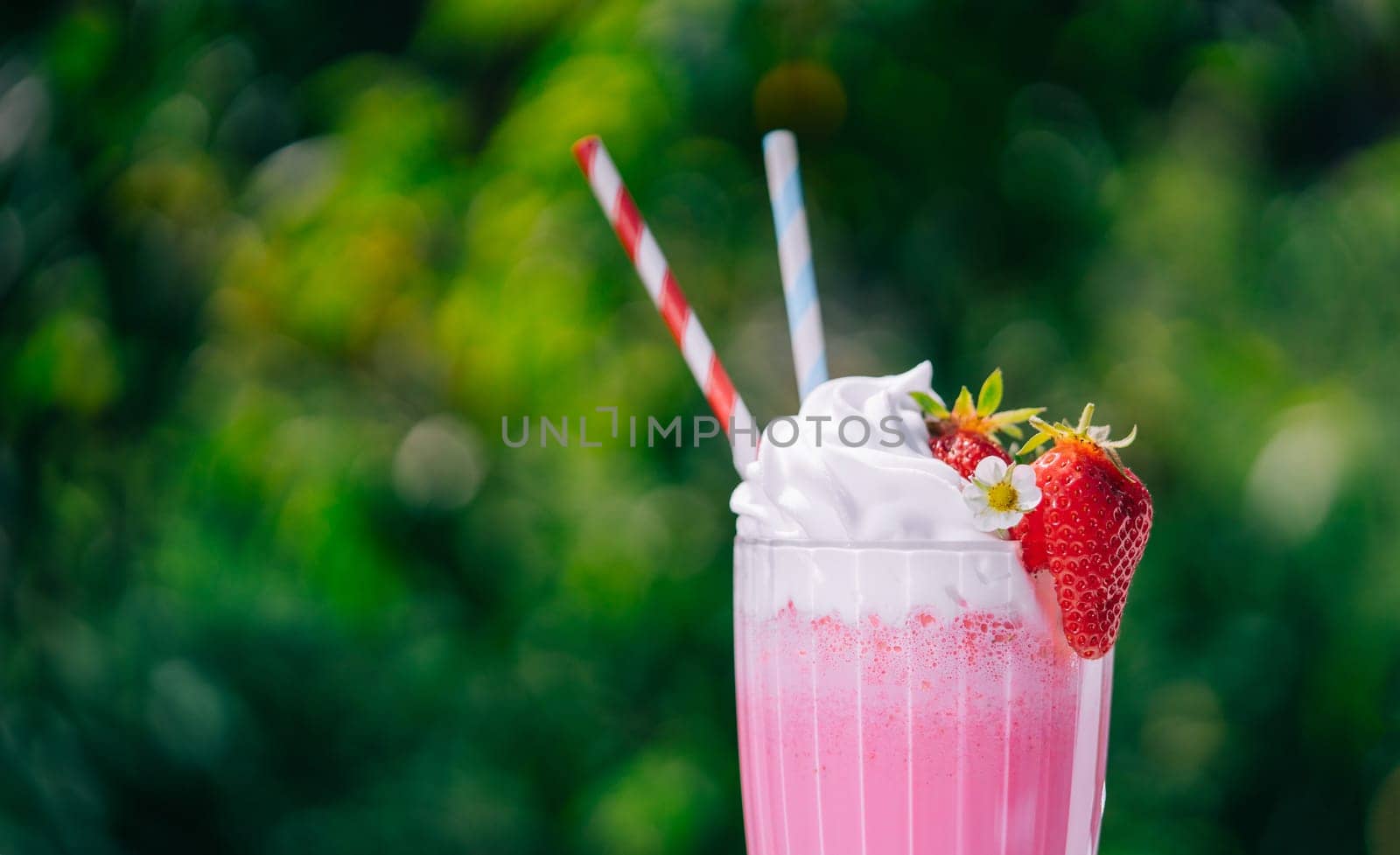 Still life - amazing strawberry milkshake cocktail with straw on nature backdrop by kristina_kokhanova
