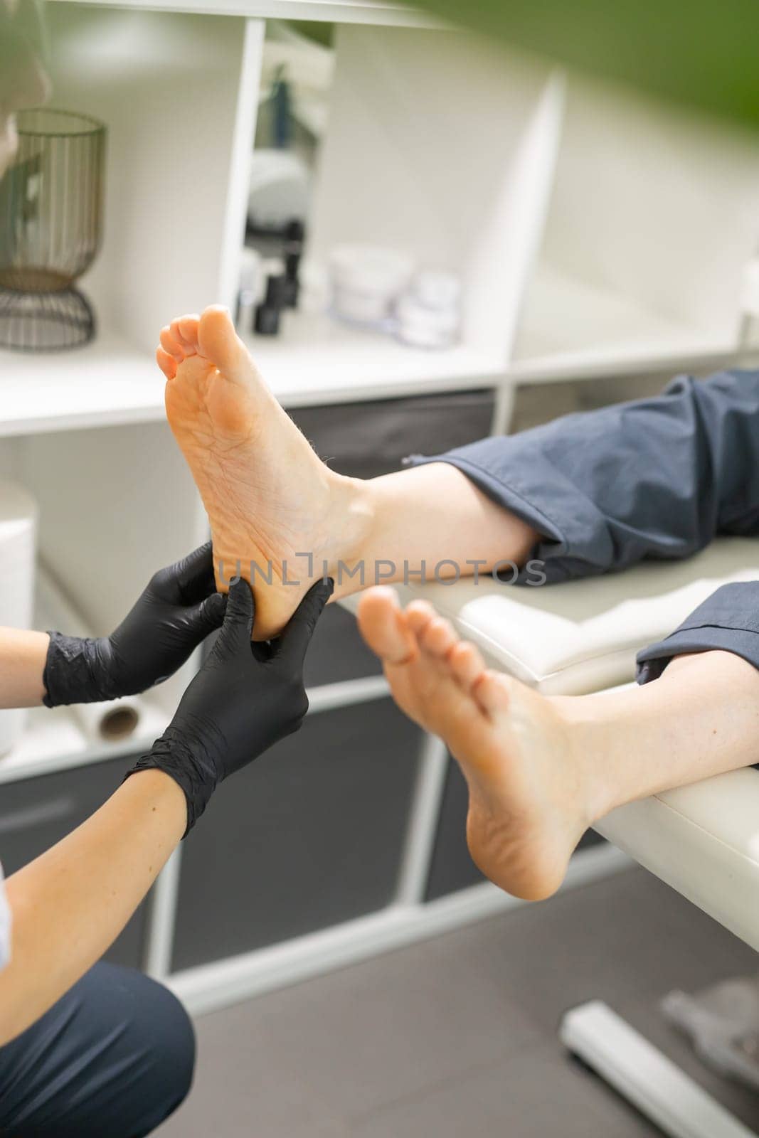 Woman doing foot peeling in pedicure SPA salon. Sugar scrub and relax beauty procedure.