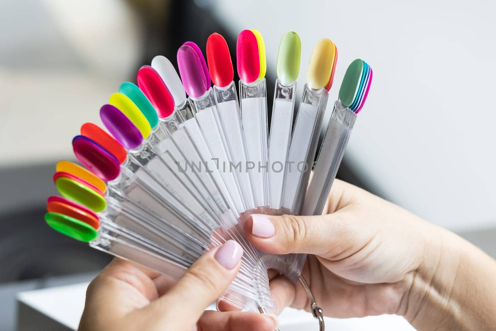 Collection of nails color polish samples. A palette of nail designs of different colors with gel polish. Transparent tips with nail polish samples. Demonstration fan-shaped palette of color shades