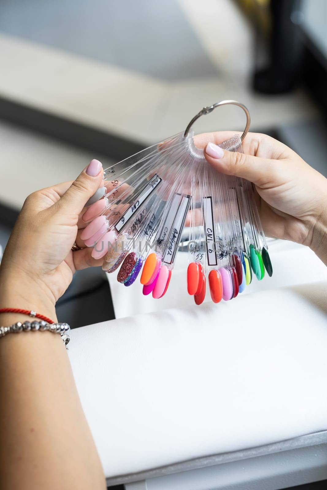 Collection of nails color polish samples. A palette of nail designs of different colors with gel polish. Transparent tips with nail polish samples. Demonstration fan-shaped palette of color shades