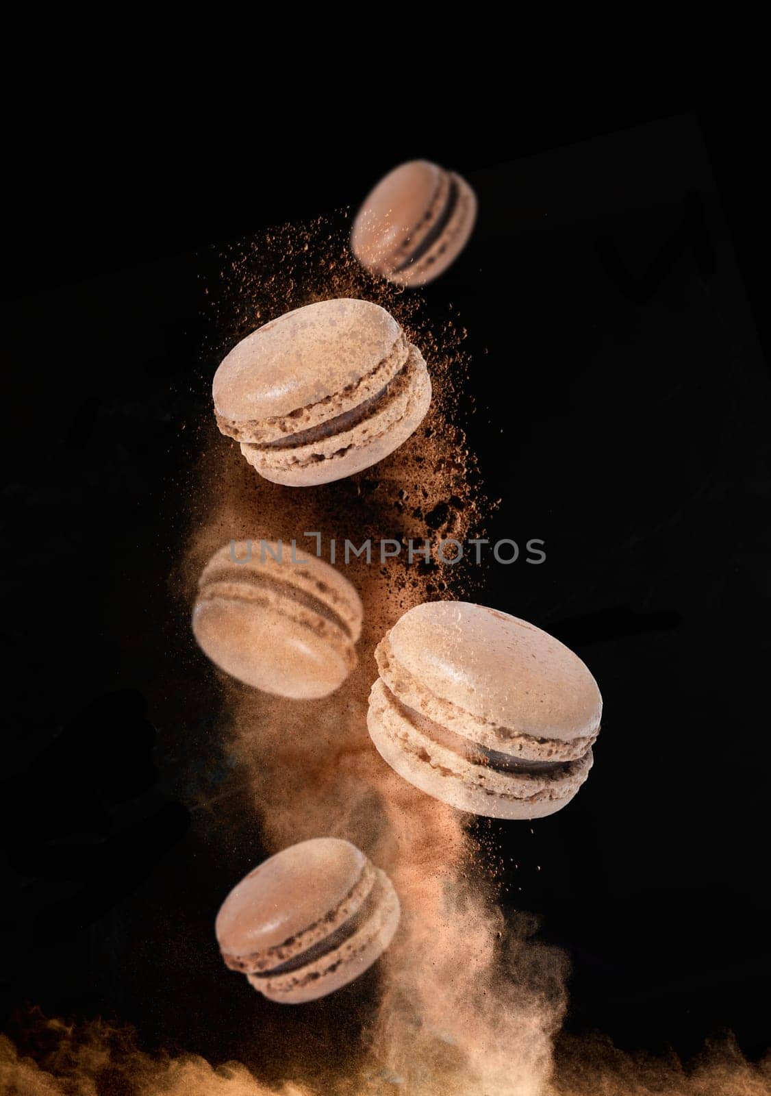 Chocolate macaroons levitate in a cloud of cocoa on a black background, delicious dessert