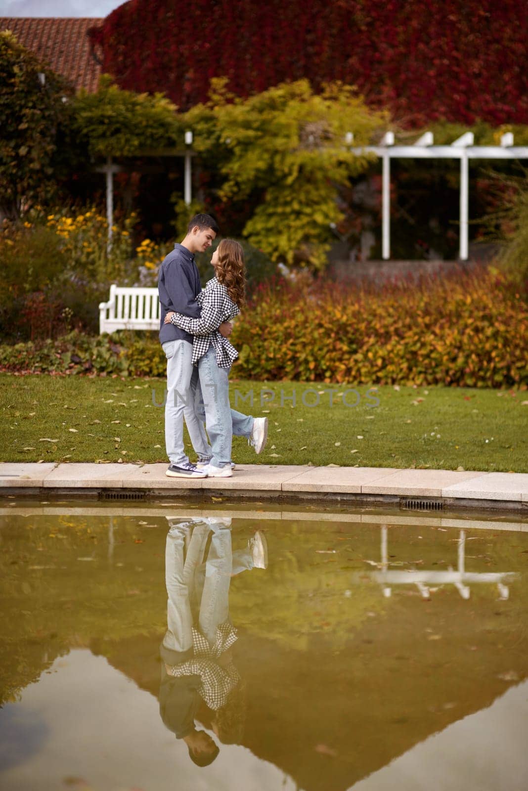 A couple in love hugs on the shore of a city pond in the European town. love story against the backdrop of autumn nature. Embraced by Love: Couple by the City Pond in a European Town. Autumn Affair: Romance on the European City Pond. Couple's Affection in Autumn by Andrii_Ko