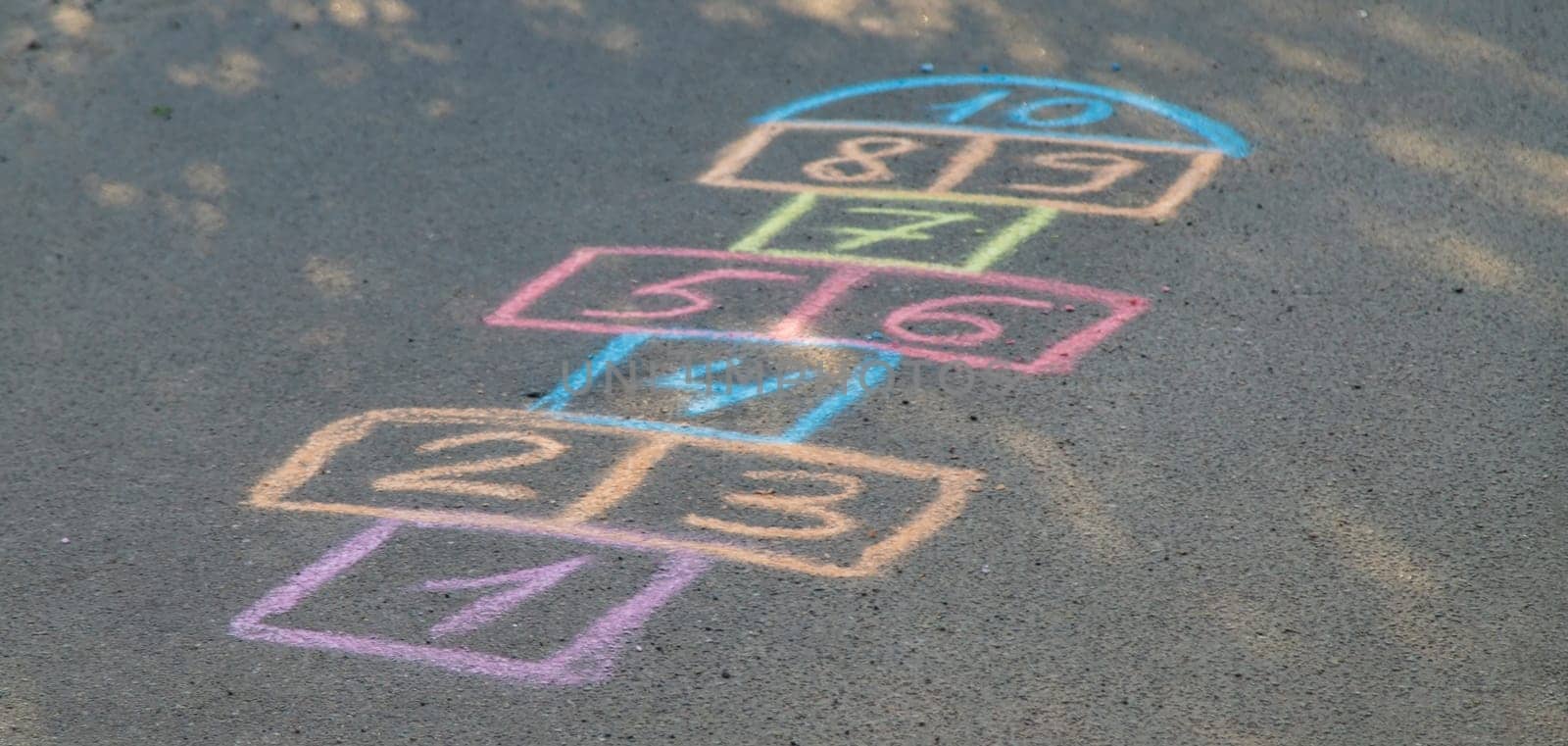 Backyard classics on an asphalt floor with chalk drawn numbers and squares. Selective focus. nature