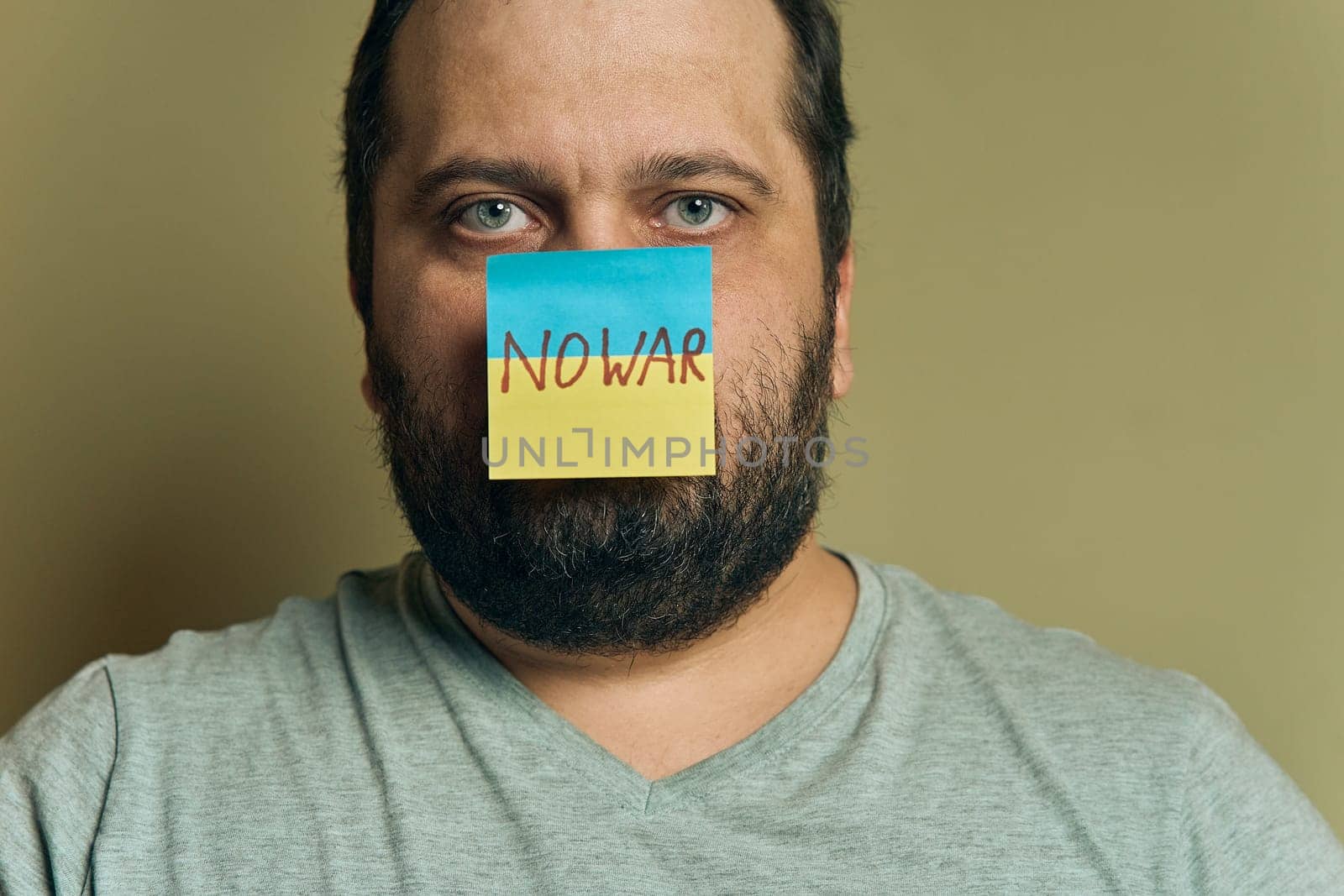 A bearded European man with a sticker attached to the nose, in the form of a Ukrainian flag with the inscription no war by snep_photo