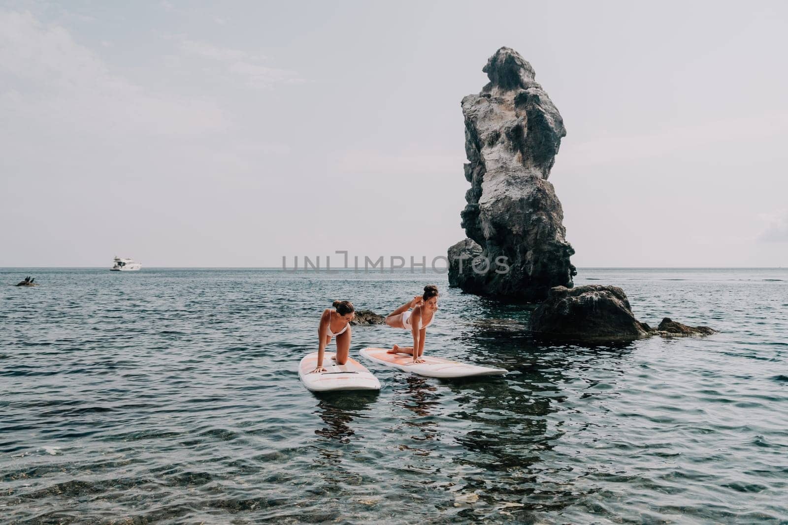 Woman sup yoga. Middle age sporty woman practising yoga pilates on paddle sup surfboard. Female stretching doing workout on sea water. Modern individual hipster outdoor summer sport activity