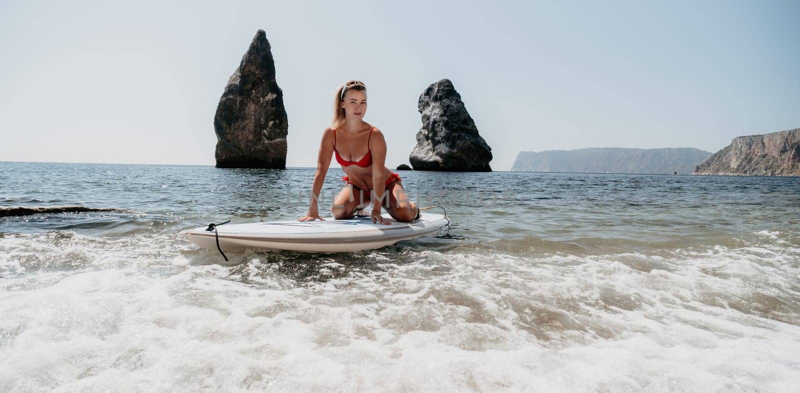 Woman sea sup. Close up portrait of happy young caucasian woman with blond hair looking at camera and smiling. Cute woman portrait in red bikini posing on sup board in the sea by panophotograph