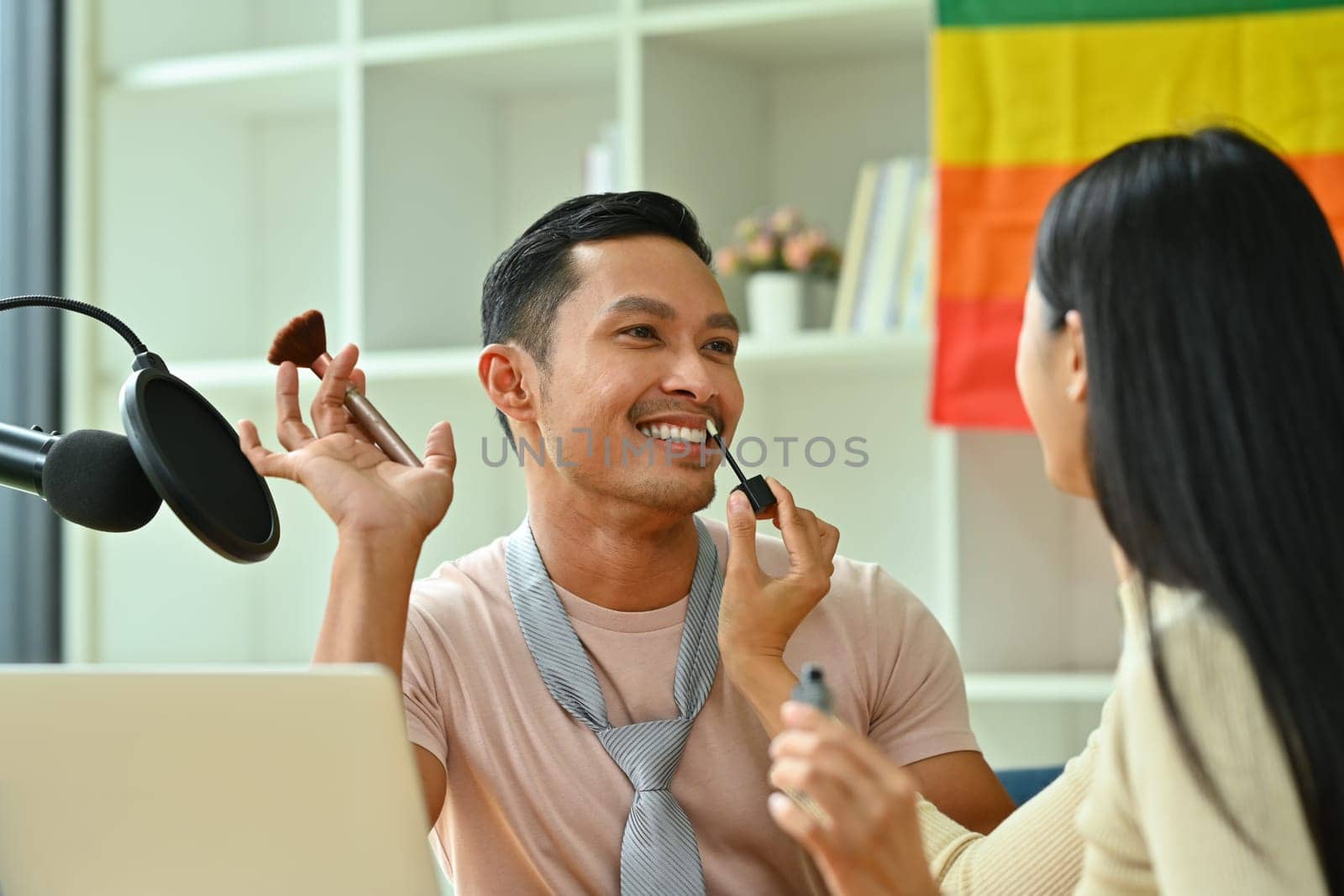 Young woman applying lip gloss on friends lips. LGBTQ lifestyle and friendship concept.