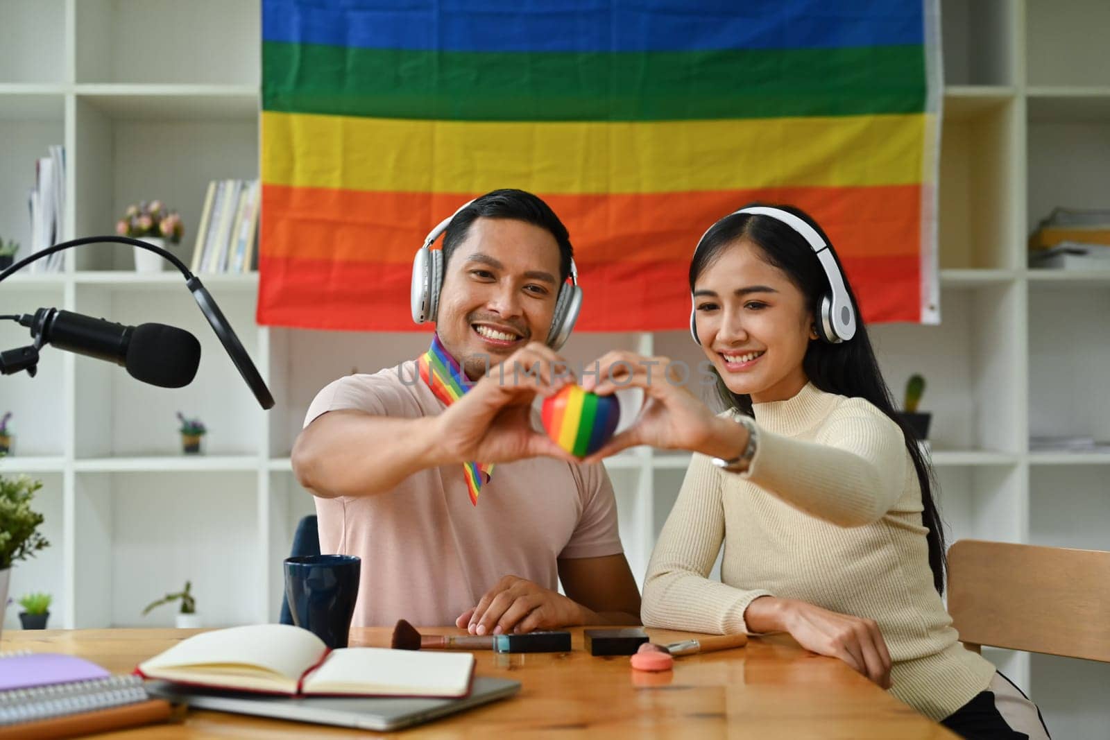 Male and female hands holding rainbow heart with smiling face. LGBTQ, human rights and equality social.