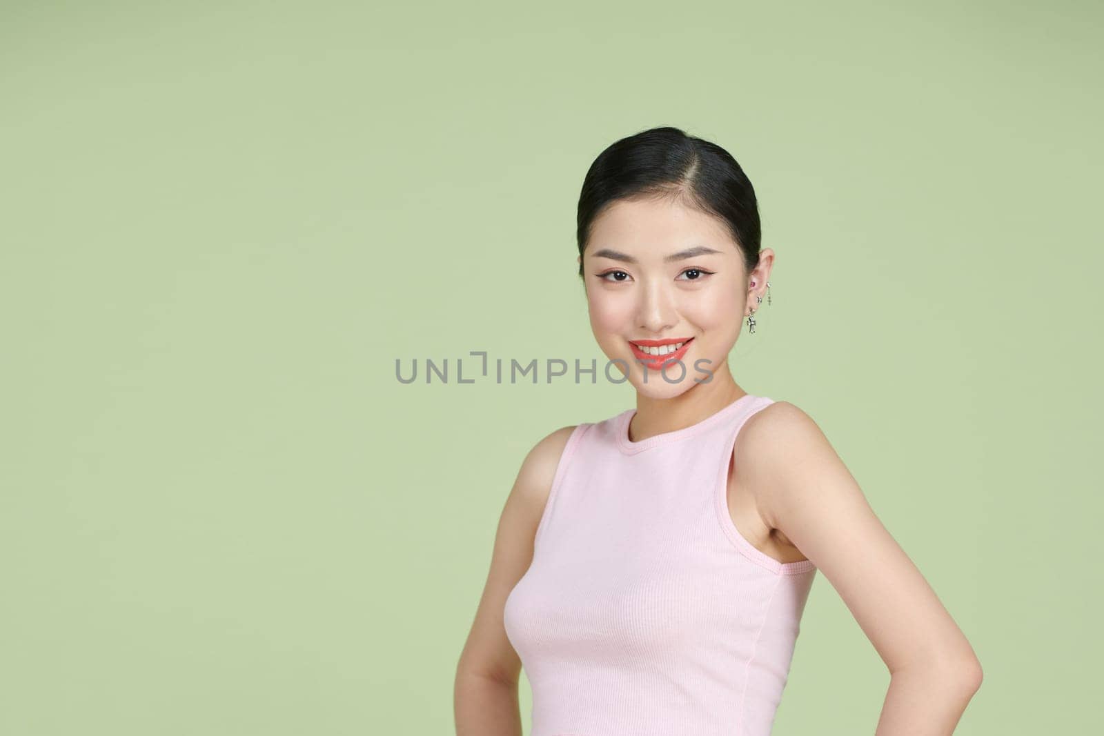 Beautiful young woman is looking at camera and smiling, standing with akimbo