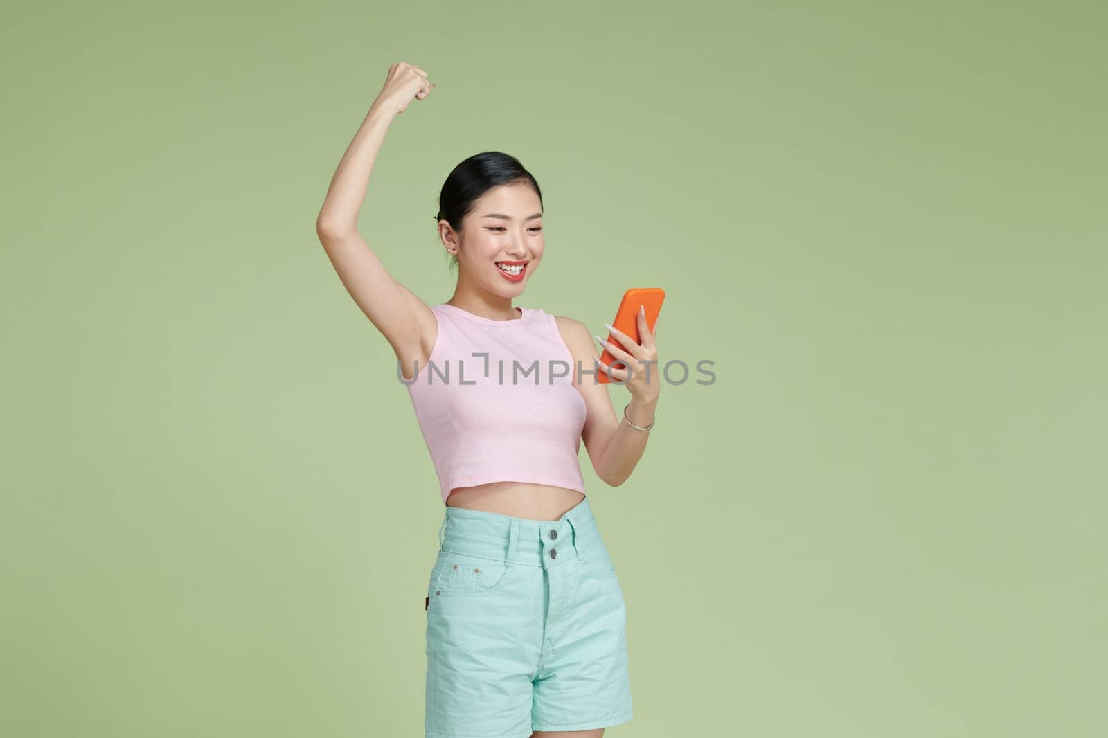 Happy Asian woman holding a smartphone and winning the prize.