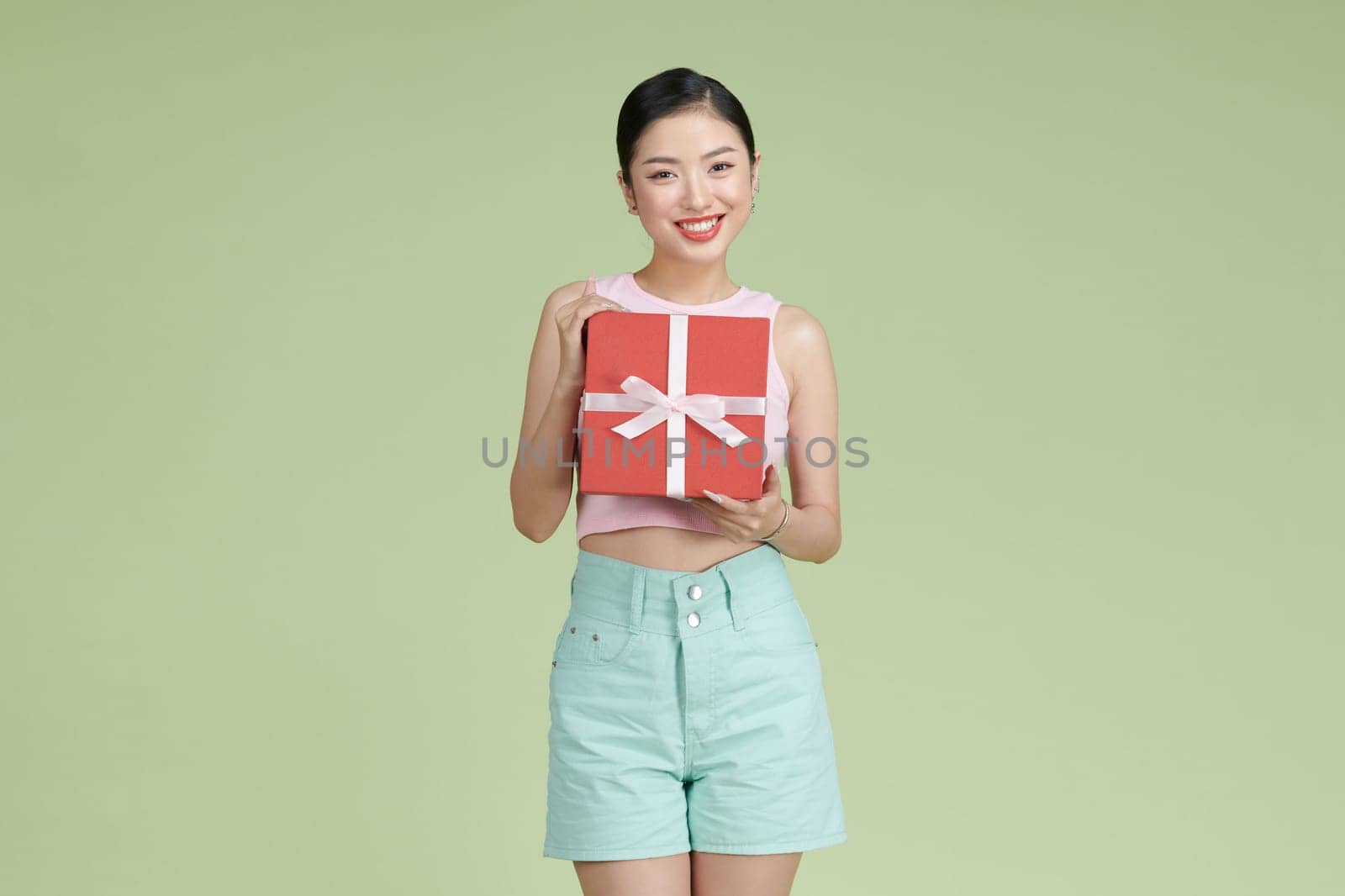 Young asian woman holding gift smiling with a happy and cool smile on face