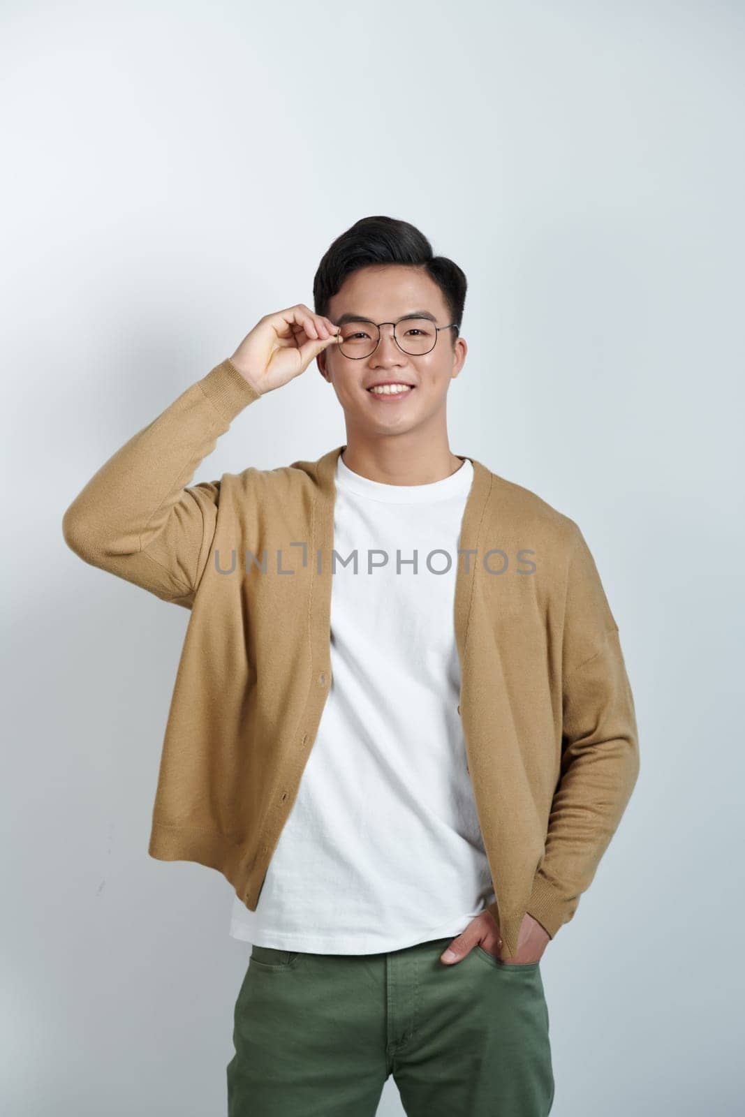 Handsome stylish young man touching eyeglasses and posing