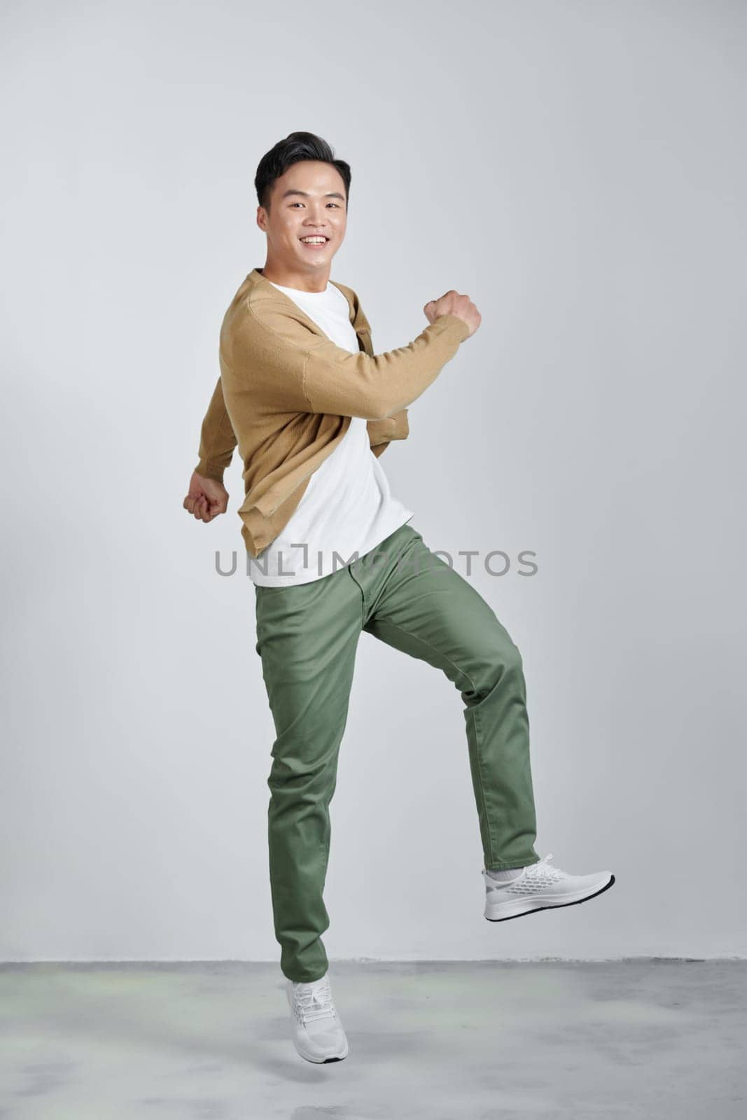 Happy excited young Asian man jumping isolated on white studio background