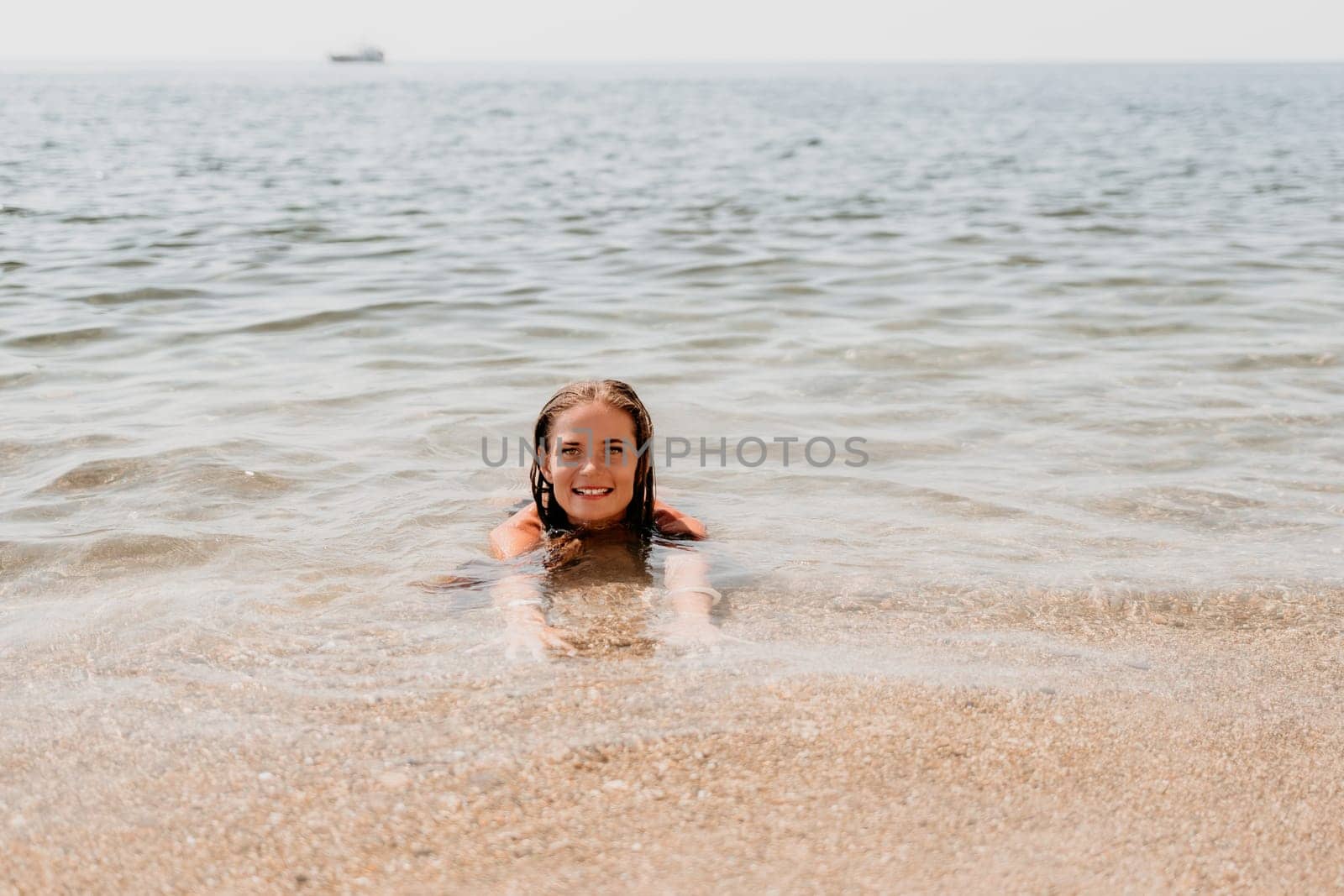 Woman travel sea. Young Happy woman in a long red dress posing on a beach near the sea on background of volcanic rocks, like in Iceland, sharing travel adventure journey