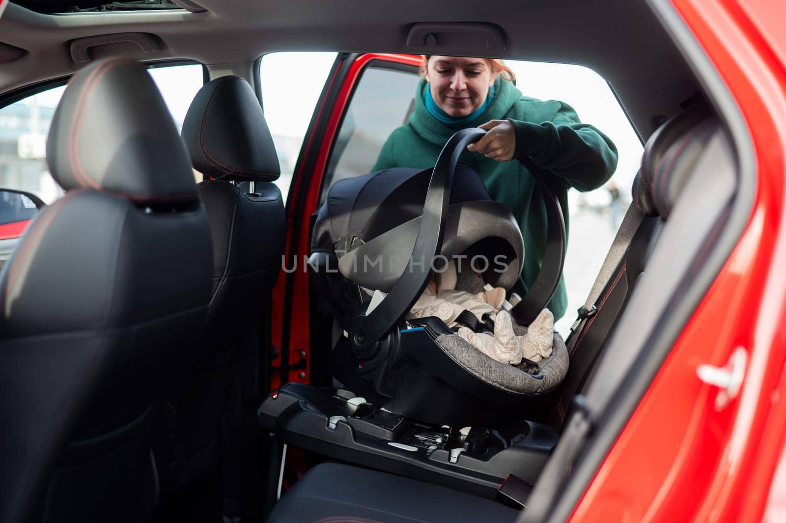 A Caucasian woman puts a child seat with a newborn baby in the car. Quick fastener. by mrwed54