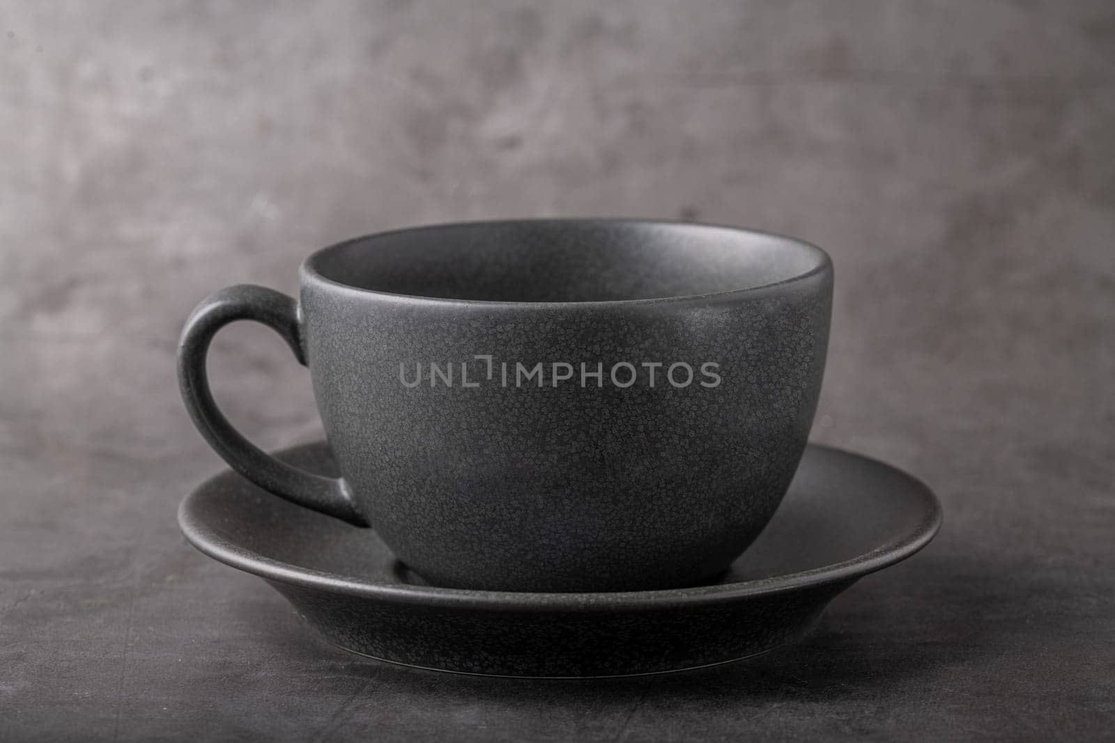 Empty black porcelain cup on gray stone background