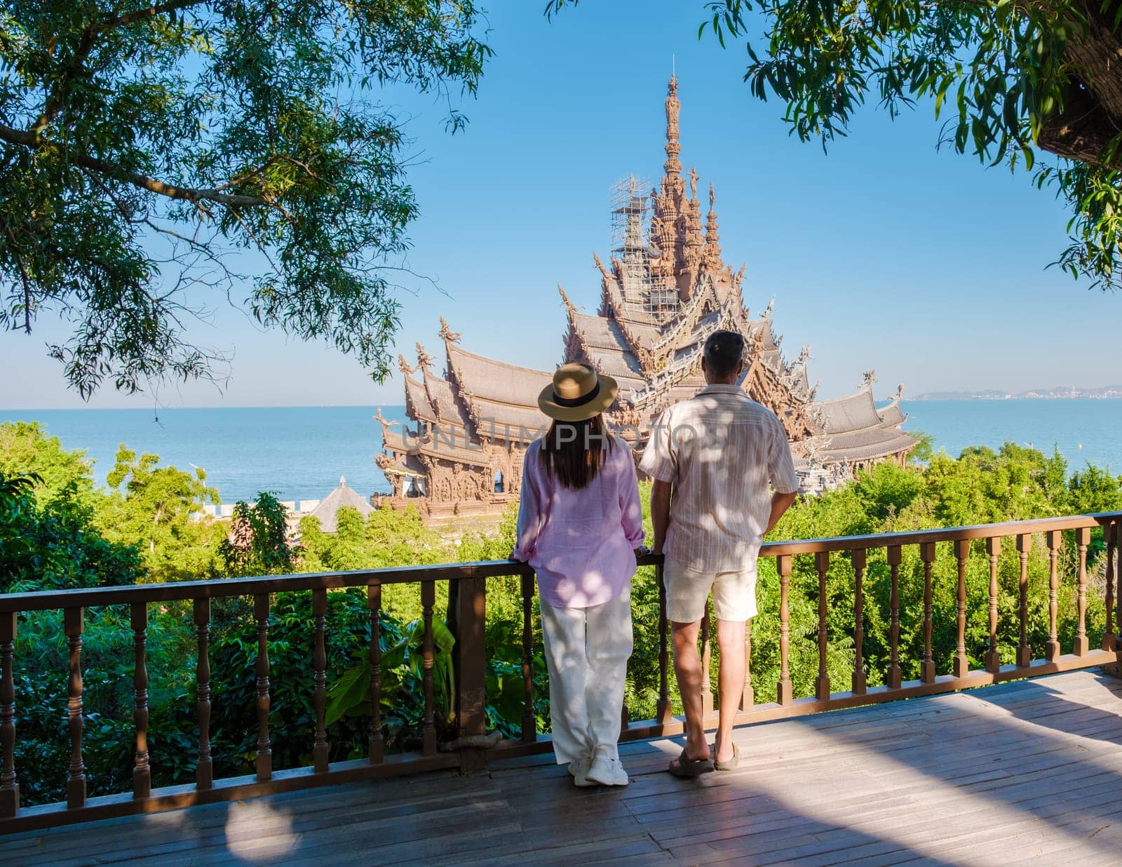 A couple of men and women visit The Sanctuary of Truth wooden temple in Pattaya Thailand. a wooden temple construction located at the cape of Naklua Pattaya City Chonburi Thailand