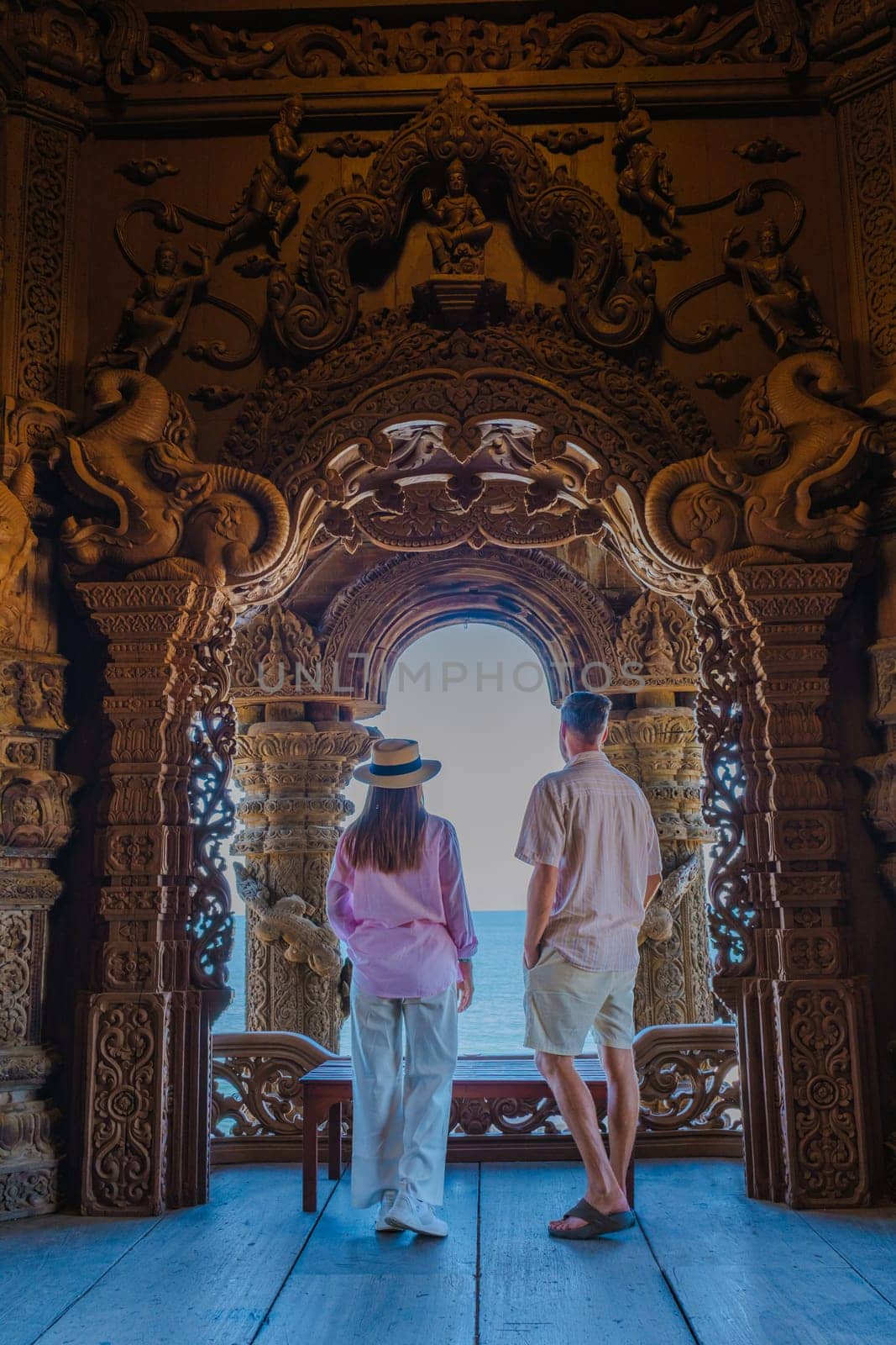 A couple of men and women visit The Sanctuary of Truth wooden temple in Pattaya Thailand. a wooden temple construction located at the cape of Naklua Pattaya City Chonburi Thailand