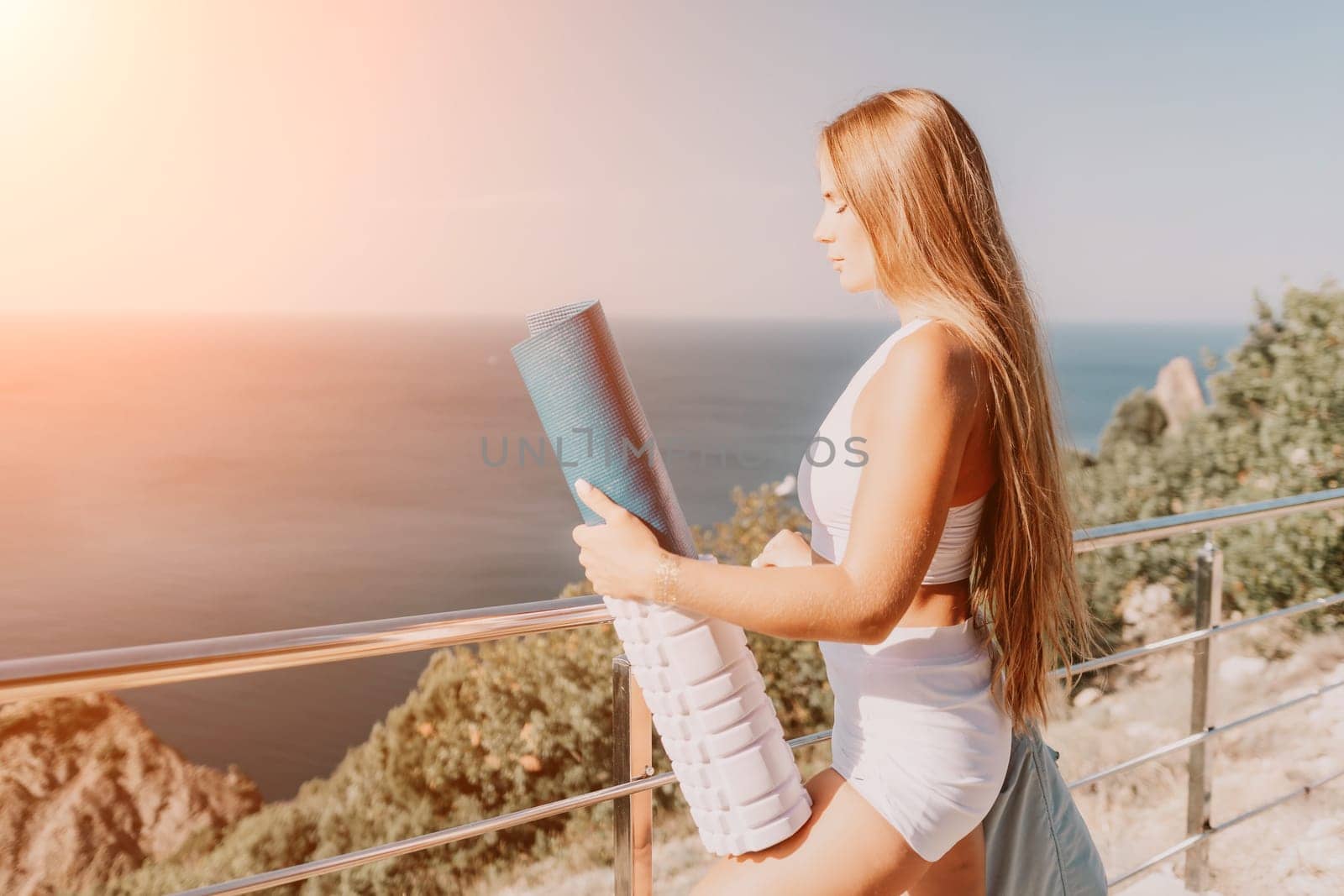 Fitness woman sea. Outdoor workout on yoga mat in park near to ocean beach. Female fitness pilates yoga routine concept. Healthy lifestyle. Happy fit woman exercising with rubber band in park.