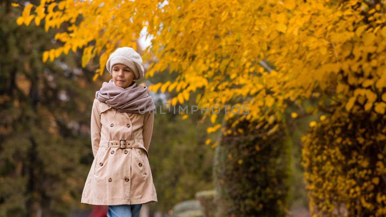 Caucasian girl in a beige coat and beret walks in the park in autumn. by mrwed54