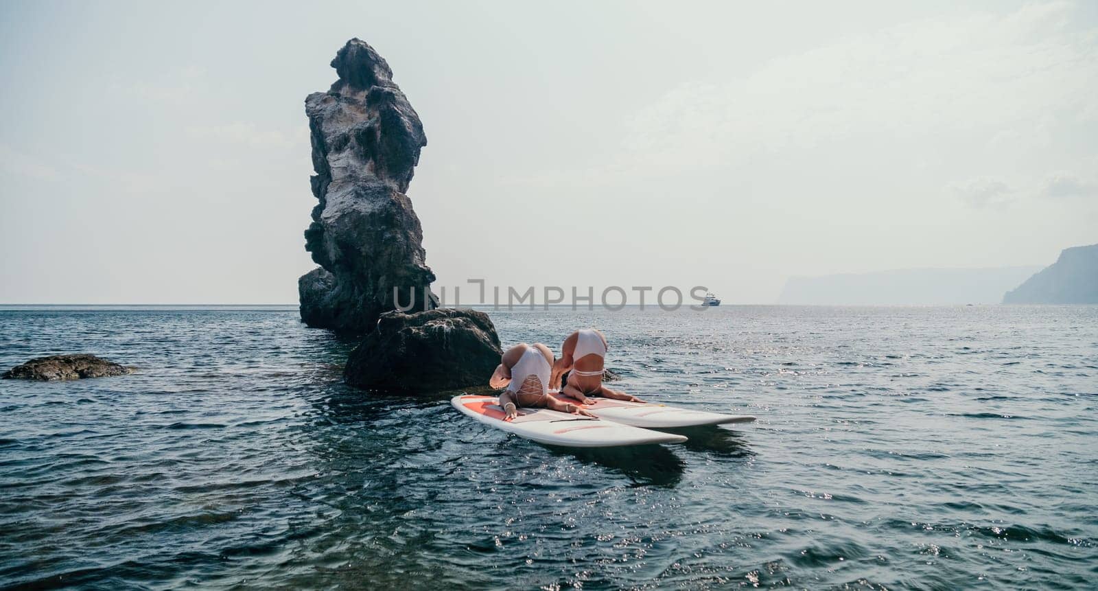 Woman sup yoga. Happy sporty woman practising yoga pilates on paddle sup surfboard. Female stretching doing workout on sea water. Modern individual female hipster outdoor summer sport activity. by panophotograph