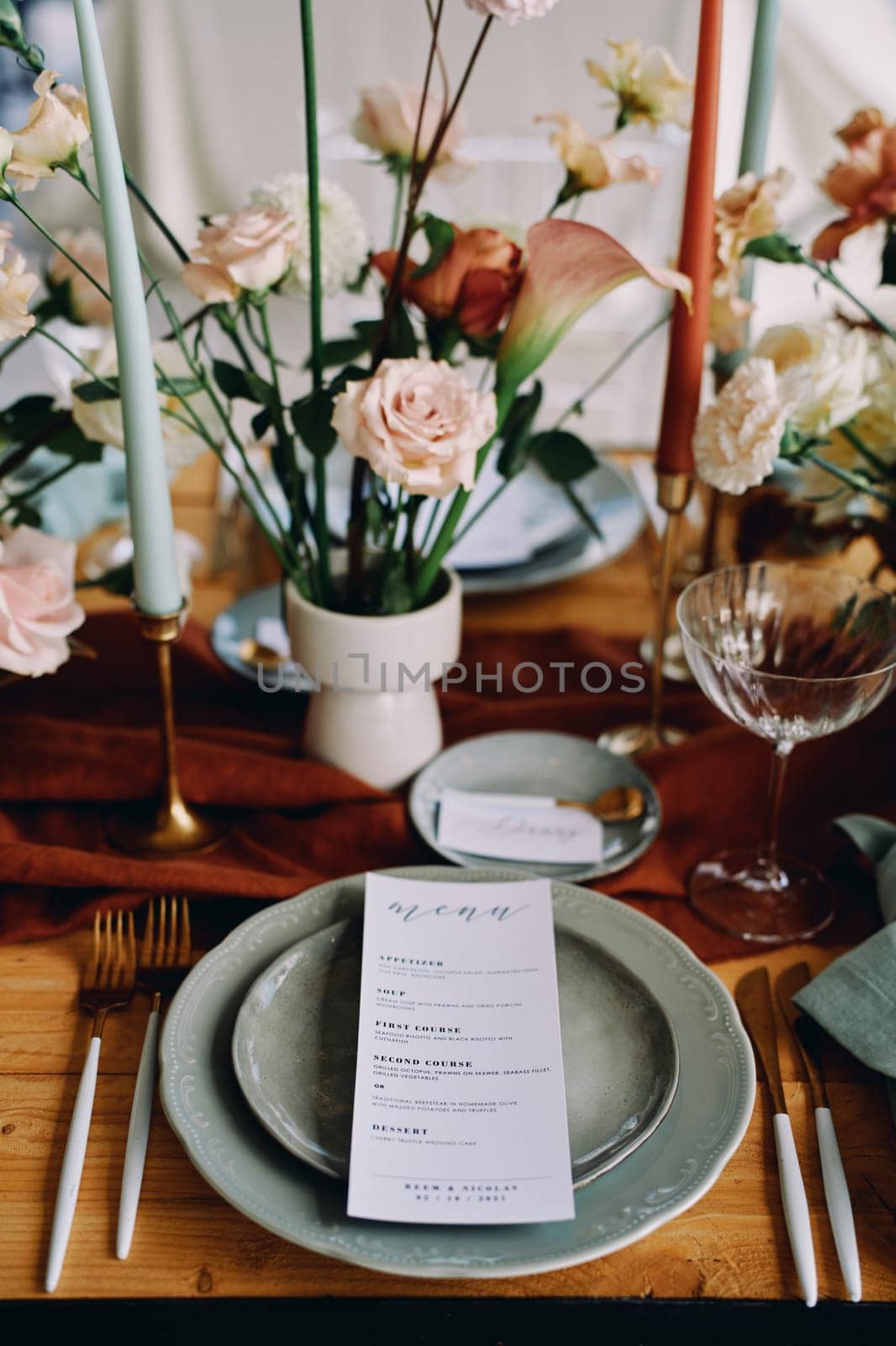 Festive menu lies on a plate on a served table near a bouquet of flowers. High quality photo