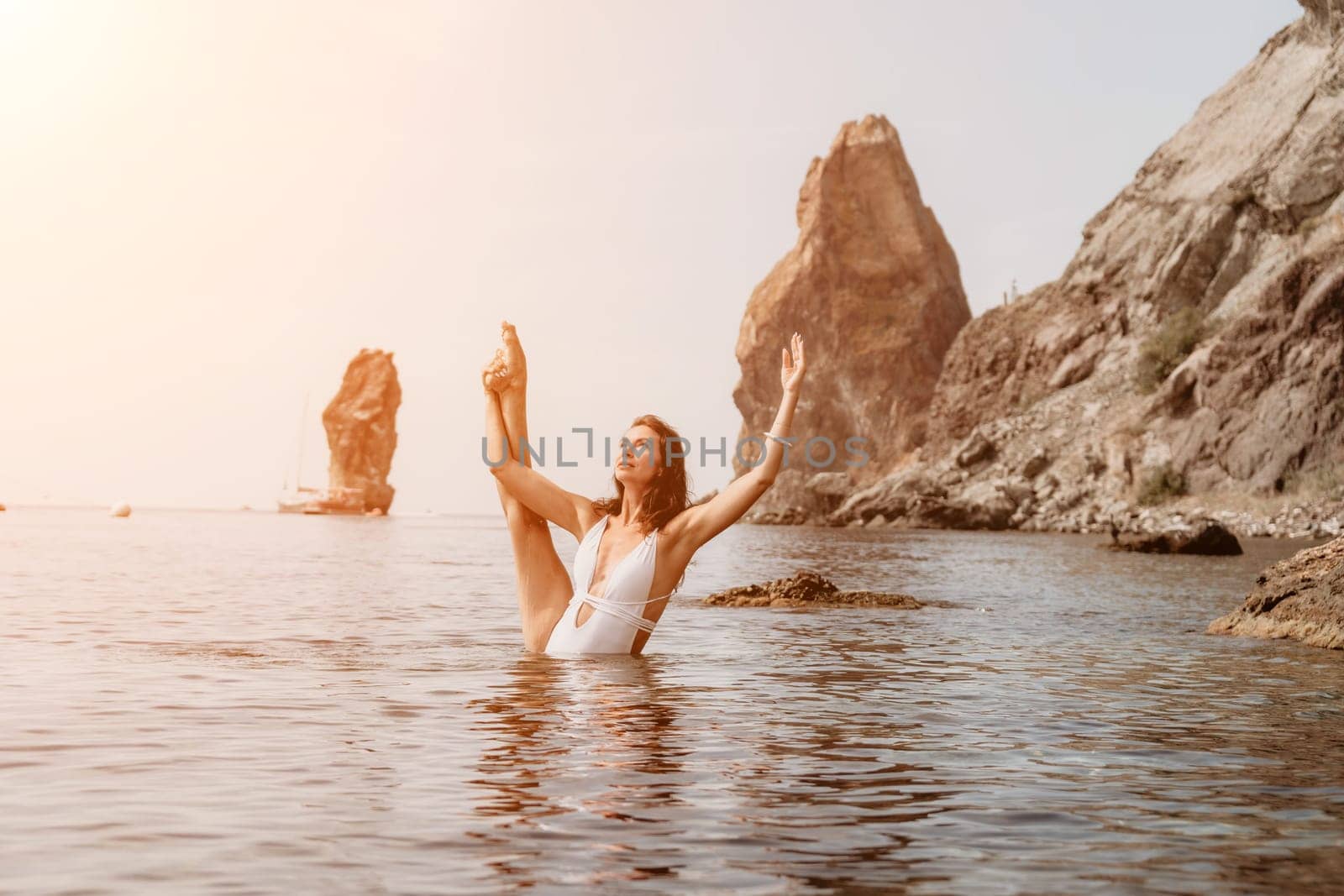 Woman sea fitness. Happy woman in a white bikini performing pilates in the sea on the beach. Female fitness yoga routine concept. Healthy lifestyle. by panophotograph