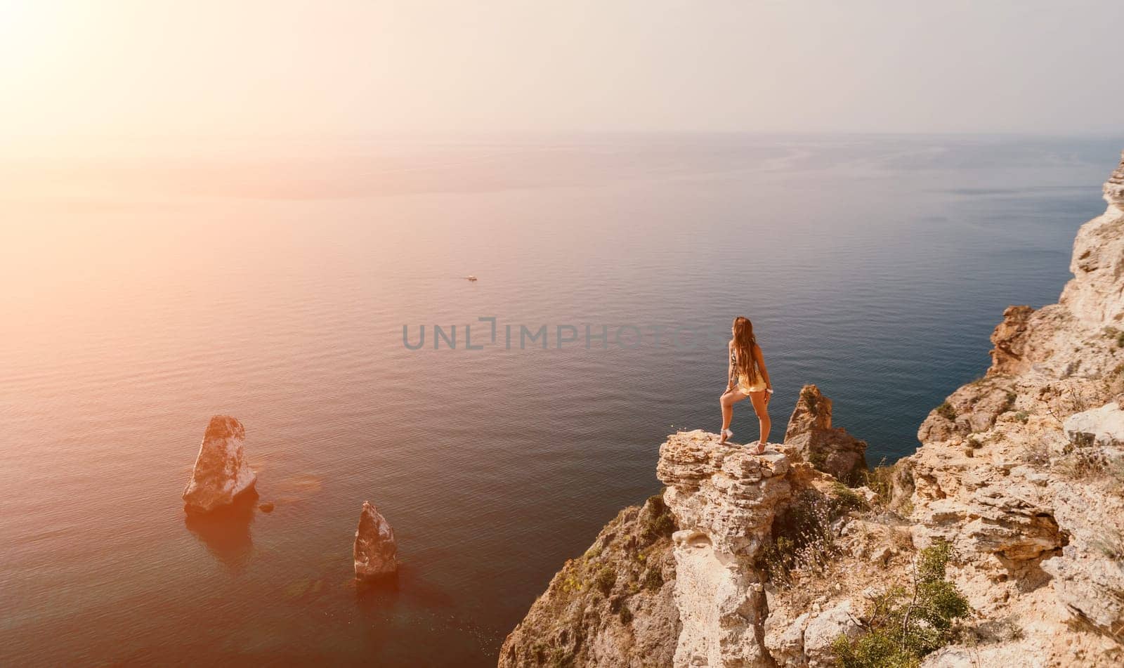 Woman travel sea. Happy tourist taking picture outdoors for memories. Woman traveler looks at the edge of the cliff on the sea bay of mountains, sharing travel adventure journey.