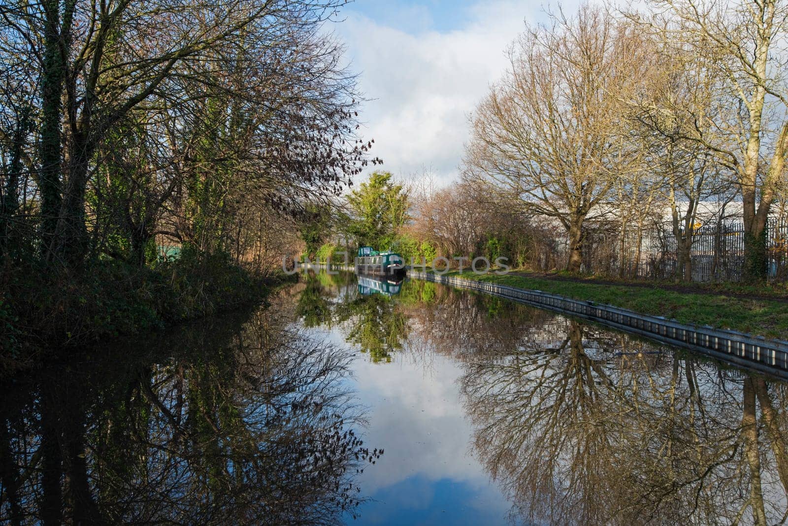 View from a narrowboat travelling in English rural countryside scenery on British waterway canal with moored boat