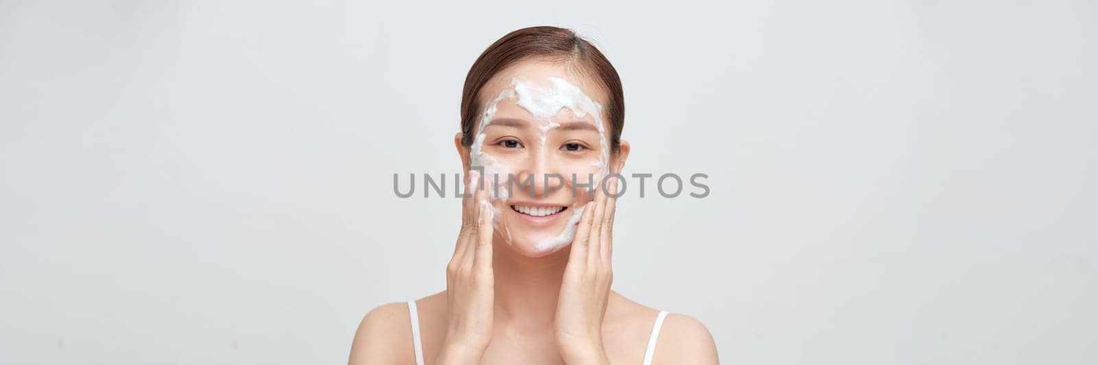 Satisfied girl with bare shoulders applying cleansing beauty product on cheeks. Banner