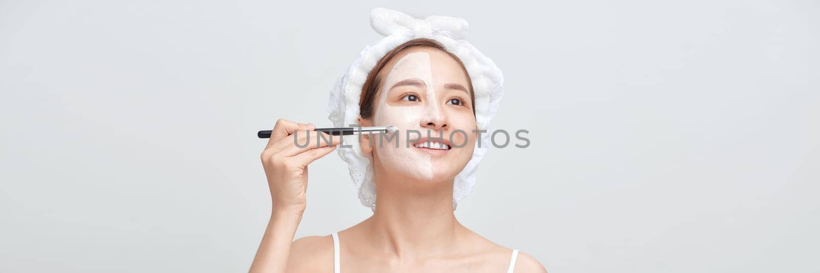 Banner of woman with a towel on her head apply a cleansing clay mask on her face by makidotvn