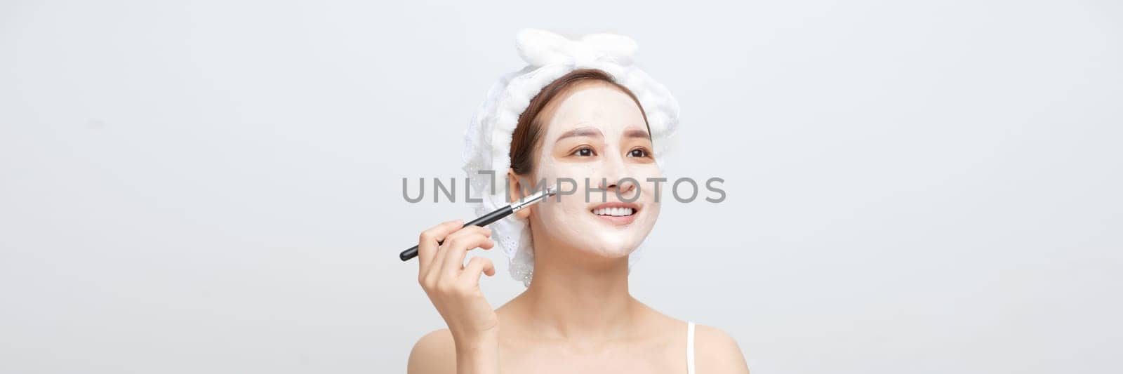 Banner of Beautiful woman having clay facial mask apply by beautician. by makidotvn