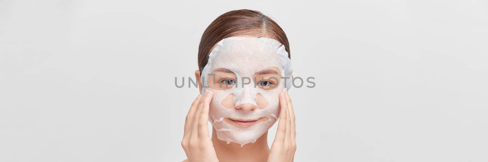 Girl taking care of skin complexion with sheet mask on her face. by makidotvn