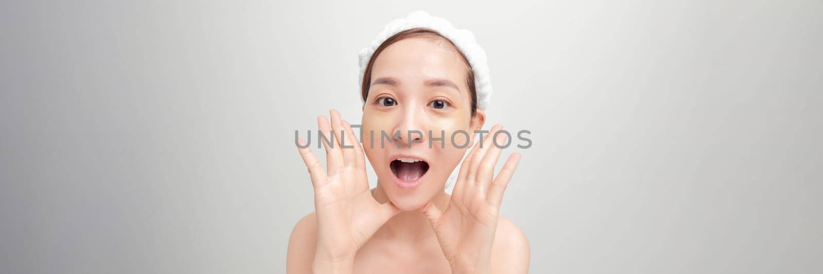 Satisfied woman with collagen patches on clear radiant face skin on light background. by makidotvn