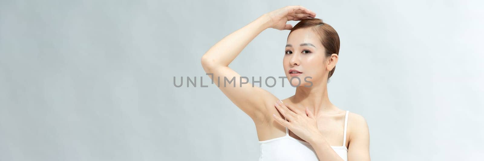 Young Asian woman lifting hands up to show off clean and hygienic armpits or underarms. Banner