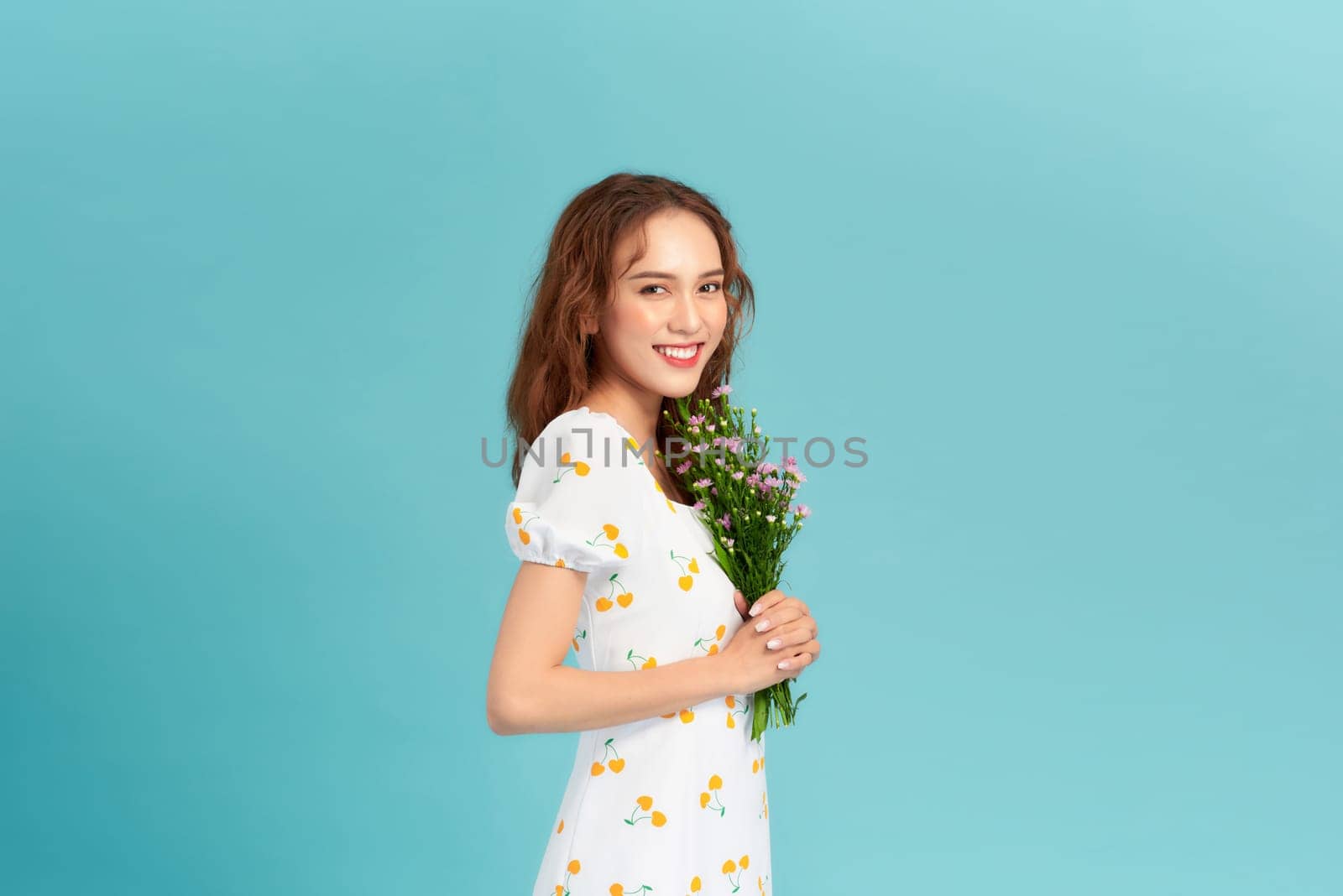 Beautiful cheerful young girl wearing summer dress, holding bouquet of wildflowers by makidotvn