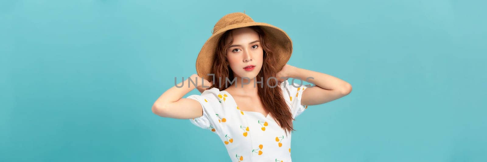 beautiful attractive stylish woman in straw hat posing on blue background 