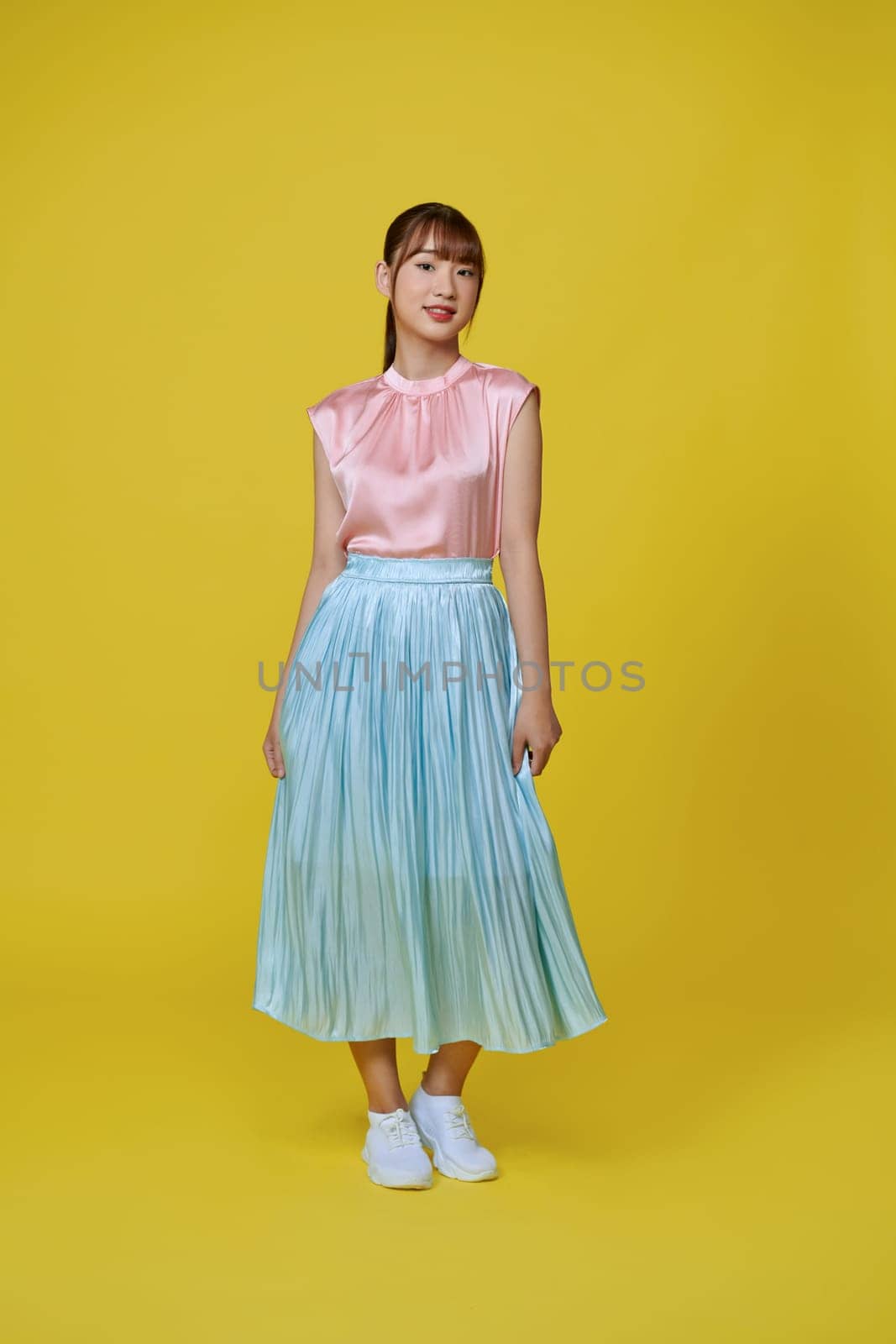 Full length image of young Asian woman wearing trendy dress on pink background