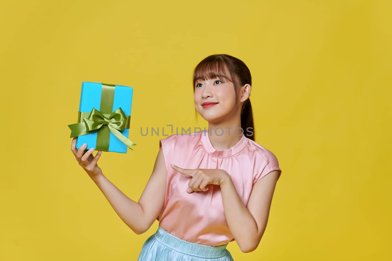 Beautiful girl posing with gift and smiling, showing wrapped present box