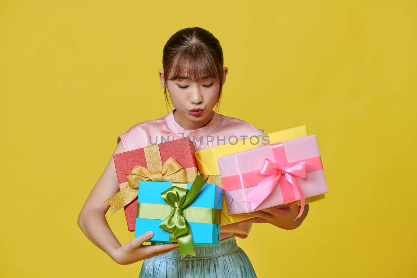 Portrait of beautiful, stylish woman emotionally posing with present boxes over yellow background. by makidotvn