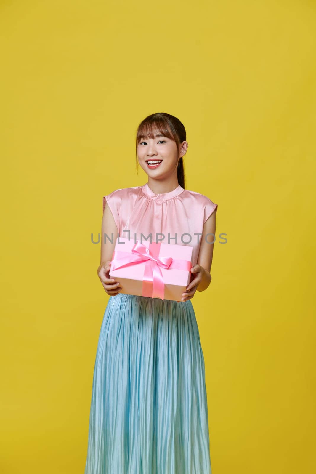Happy young woman with gift boxes on a yellow background by makidotvn
