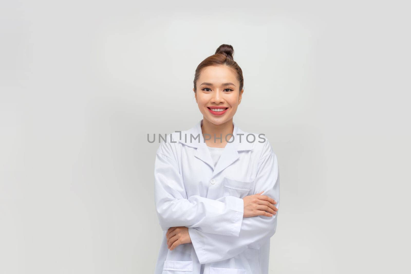 Happy young woman in lab coat on light grey background