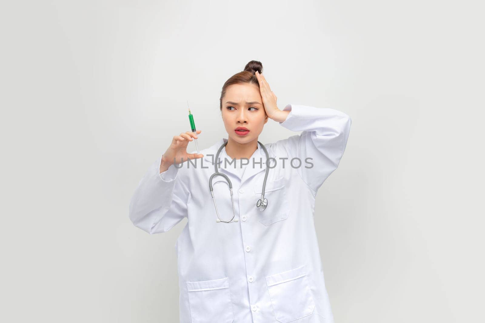 Asian woman with braids holding syringe stressed and frustrated with hand on head