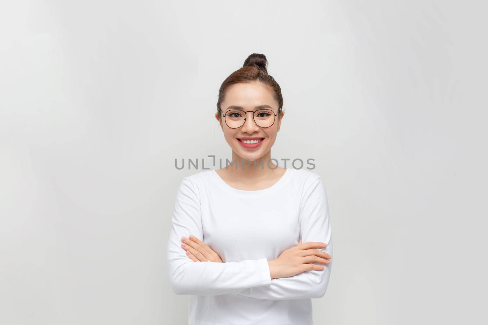 Young woman standing with arms crossed against white background