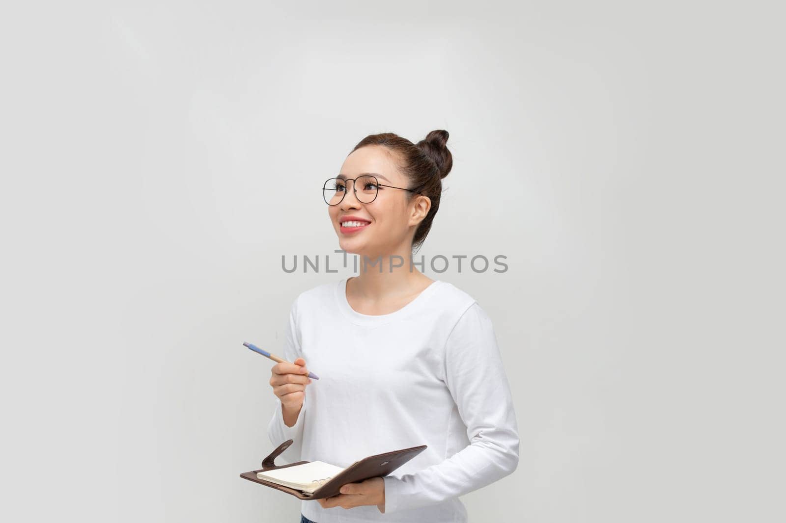 Portrait of a pensive pretty woman making notes in notepad over white