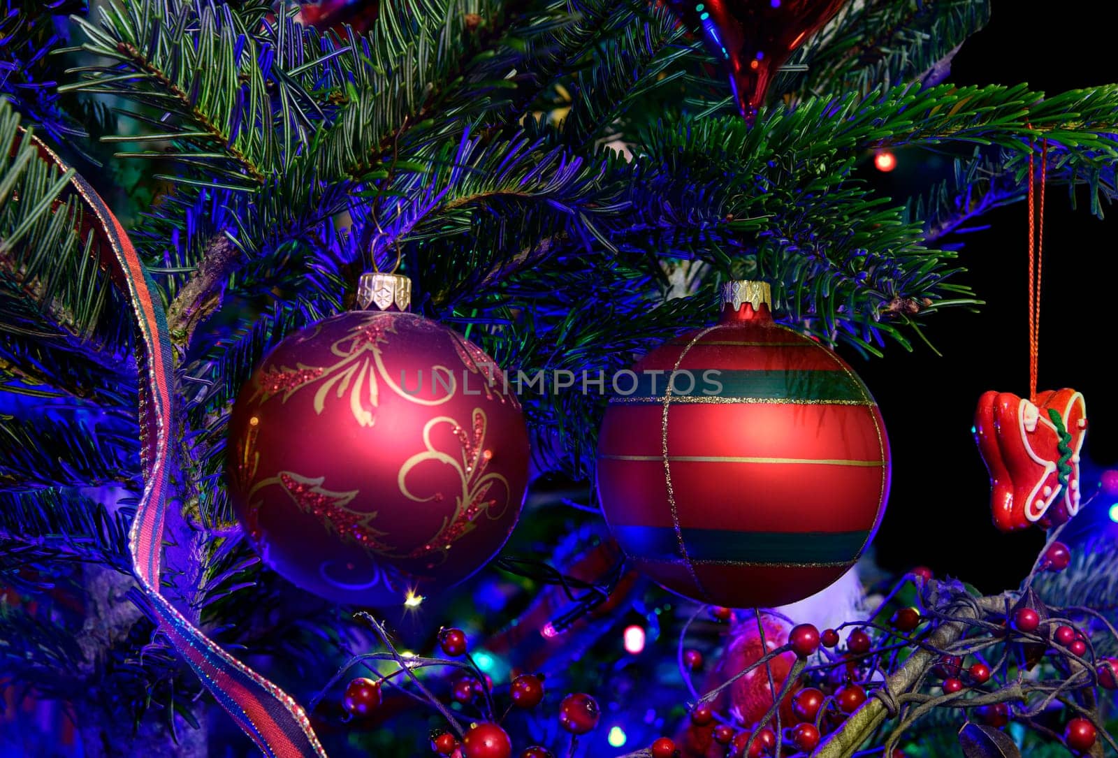 Closeup of Festive holiday decorations hanging from an illuminated Christmas tree.