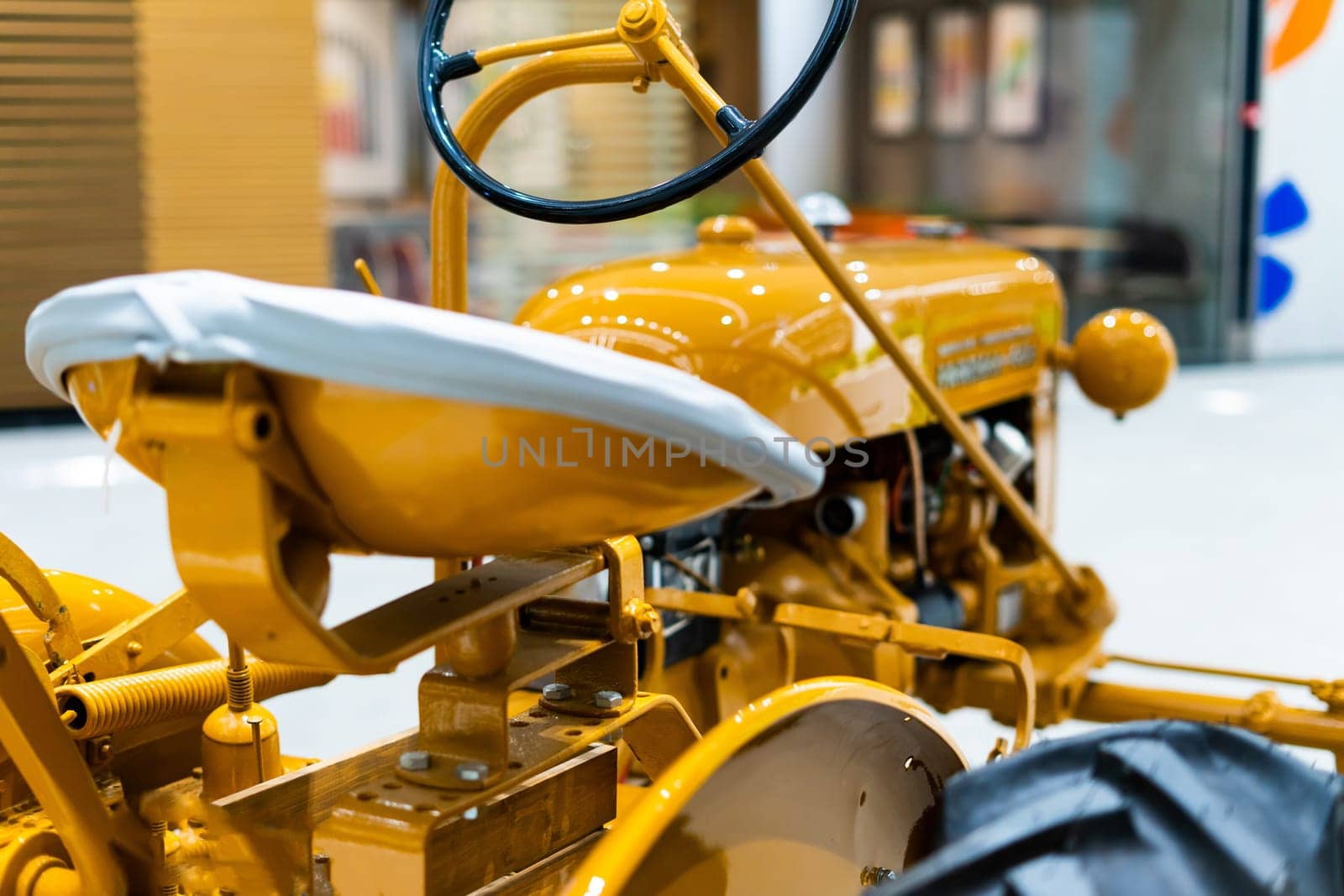 Small yellow tractor in exhibition, closeup details, wheels by Zelenin