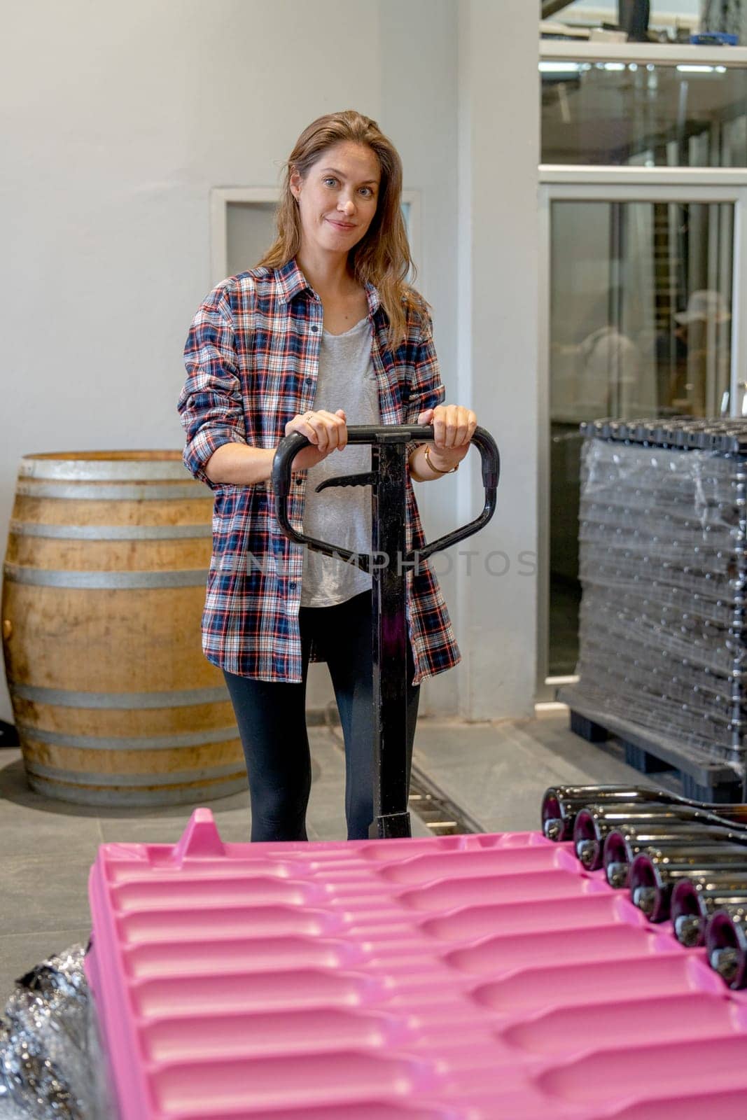 Winery worker woman hold hand of factory truck to carry the containers of wine bottle.