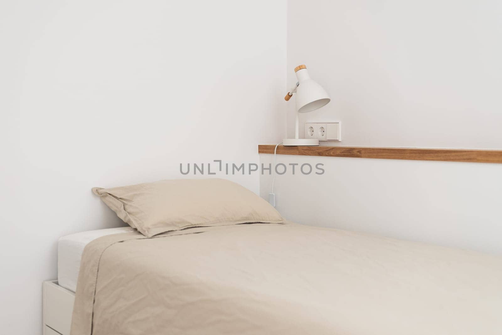 Single bed near wall shelf with night lamp in white bedroom by apavlin
